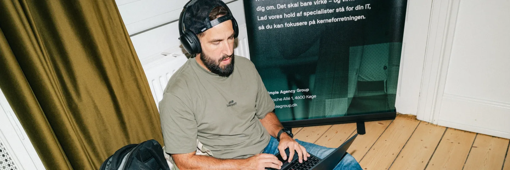 Medarbejder sidder på gulvet med hovedtelefoner og arbejder på en ny hjemmeside