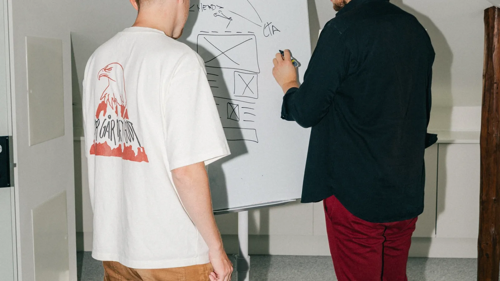 Kollega tegner en wireframe med CTA på en flipover, mens en anden kigger med